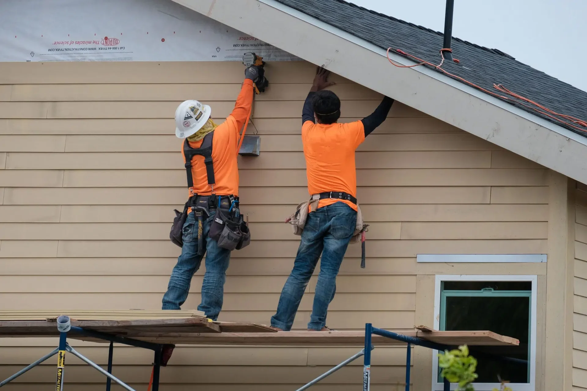 Crew installing beige vinyl siding on Ottawa home exterior