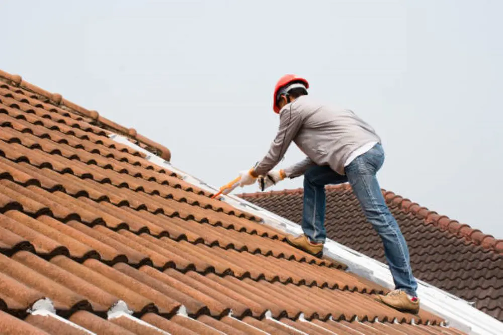 Worker sealing roof tiles during Ottawa siding project